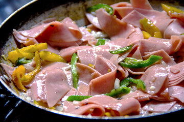 Sizzling jalapeno, ham, and yellow pepper strips in a rustic pan—rural Mexican breakfast in the making.