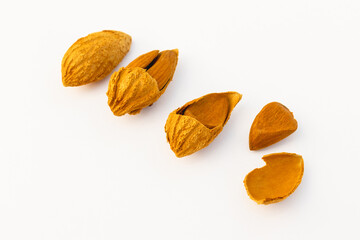 A close-up of almonds in various stages of being cracked open, showing the shells and nuts inside, placed on a white background.