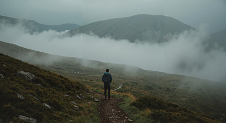 Man standing on trail in foggy mountain landscape  