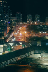 view of a bridge and a street on ground level below, with building around downtown at night