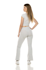 Fit woman in sportswear standing with hand on hip, back turned, looking over shoulder.