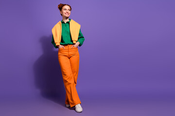 Fashionable young woman in colorful casual outfit posing with a charming smile against a vibrant purple background