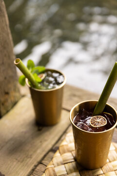 Mule cocktails garnished with dried fruit served in copper glasses and bamboo straw in tropical setting. 