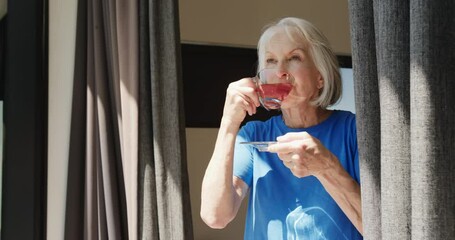 Senior woman enjoying tea by window, embracing peaceful morning solitude, at home