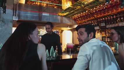 Asian bartender using strainer all ingredients alcohol liquor and syrup tasty in cocktail glass at decorated christmas trees serving refresh drink to VIP couple guest nightlife at nightclub. Vinosity.