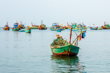 Colorful wooden fishing boats floating in the calm waters of Vietnamese harbor, early morning light