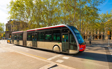 Modern Articulated City Bus Driving Through Tree-Lined Street in Barcelona © natatravel