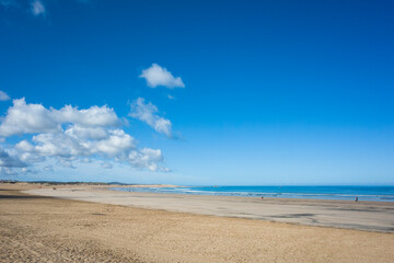 Morning view of the wide sandy beach in Essaouira, Morocco, with low tide, clear blue sky over the...