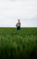Adult female farmer standing in green wheat field.