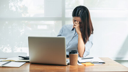 Business woman is stress and holding eyeglasses feeling of pain in the eyes, headache and tired from hard work