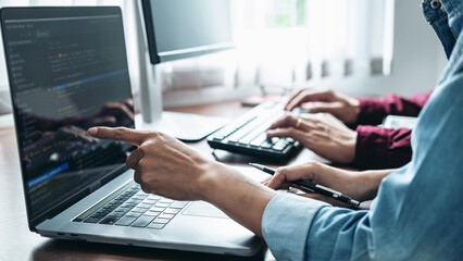 Team of asian programmer pointing code data on screen laptop to brainstorming about new website
