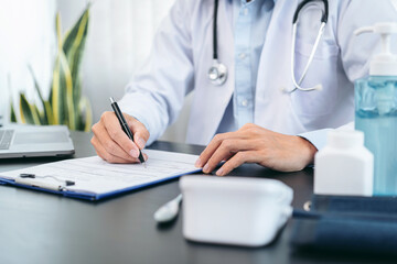 Fototapeta premium Male doctor in medical face mask is writing prescribing on document after diagnosis disease of patient while sitting