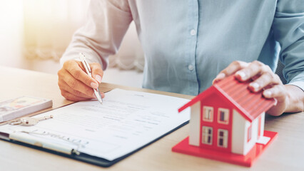 Real estate broker agent holding house model and sending to the customer after signing rental lease...
