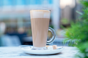 Enjoying a warm cup of creamy coffee at an outdoor cafe during a sunny afternoon in a vibrant urban setting