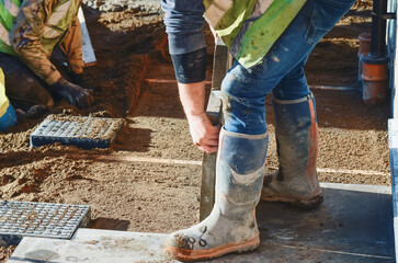 Paving works in progress as builder laying concrete paving slabs for new footpath or patio