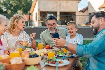 Happy family taking selfie while having lunch together in the backyard