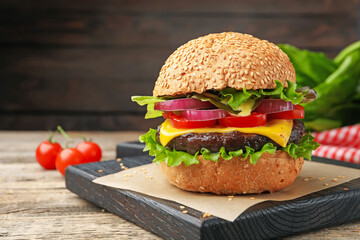 Delicious hamburger with patty and cheese on wooden table, closeup. Space for text