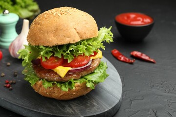 Delicious hamburger with patty served on black table, closeup. Space for text