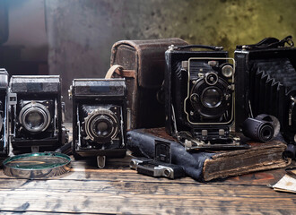 Old cameras are arranged in a composition on a wooden background, on a table.