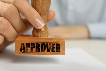 Approved. Woman stamping blank sheet of paper at table, closeup