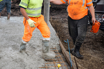 Construction worker operating a concrete pump at a job site in the daytime, focusing on the pouring...
