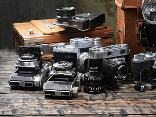 Old cameras are arranged in a composition on a wooden background, on a table.