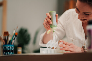 Artist pouring green paint into small containers for painting project