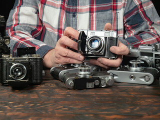 An elderly collector studies old cameras. Close-up.