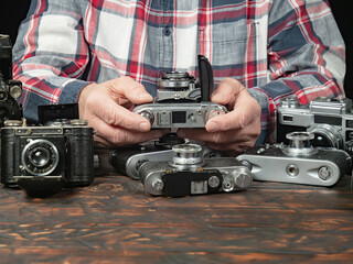 An elderly collector studies old cameras. Close-up.