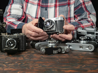 An elderly collector studies old cameras. Close-up.