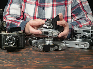 An elderly collector studies old cameras. Close-up.