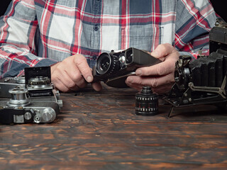 An elderly collector studies old cameras. Close-up.