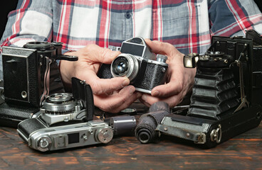 An elderly collector studies old cameras. Close-up.