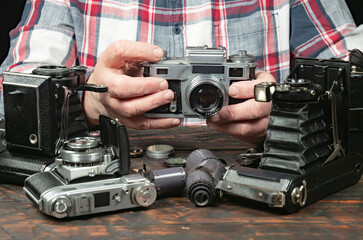 An elderly collector studies old cameras. Close-up.