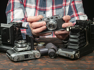 An elderly collector studies old cameras. Close-up.