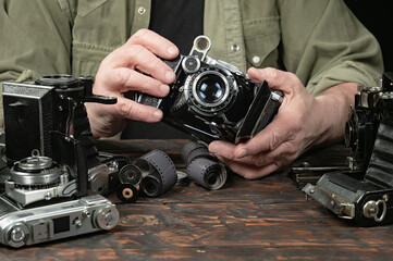 An elderly collector studies old cameras. Close-up.
