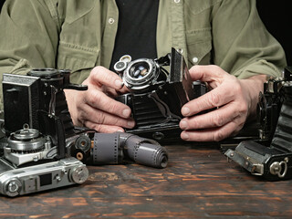 An elderly collector studies old cameras. Close-up.