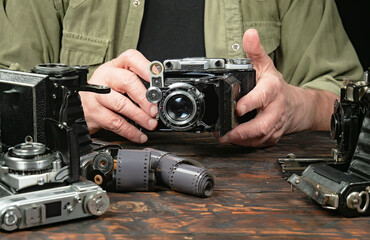 An elderly collector studies old cameras. Close-up.