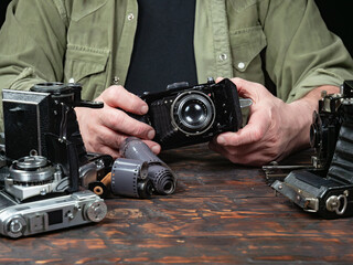 An elderly collector studies old cameras. Close-up.