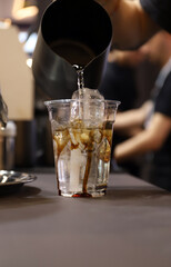 barista vertiendo agua en un café con hielo