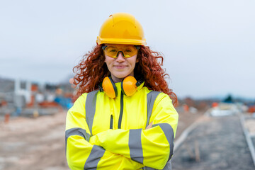 Portrait of femail Construction worker confidently overseeing a building site with equipment and...