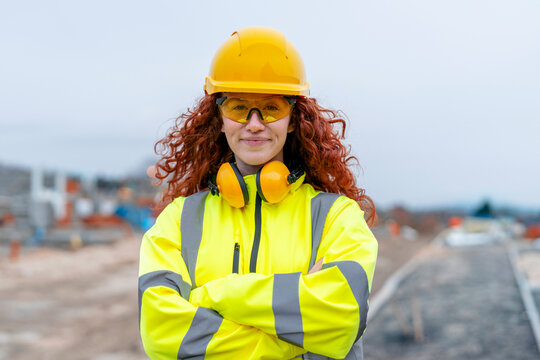 Portrait of femail Construction worker confidently overseeing a building site with equipment and crew members in the background contributing to the project