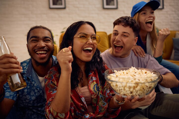 Young happy people cheering and having fun during sports match on TV at home.