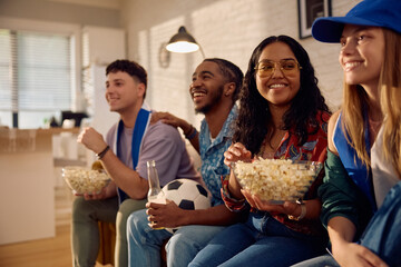 Happy Indian woman watching soccer match with her friends at home.