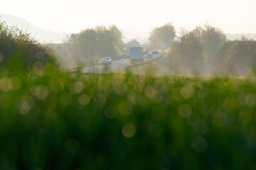 Morning rush hour traffic on the country road with lorries, trucks and cars at sunrise.