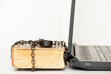 Old book in chains next to modern laptop on white background