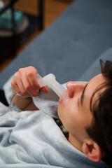 Sick man uses mouth inhaler nebulizer for flu treatment at home. Having mouth inhalation with the...
