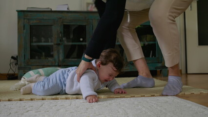 Baby being gently picked up from mat after tactile playtime, transitioning from independent...