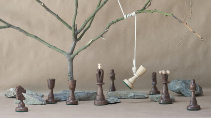 chess piece white rook hanging on noose among black chess pieces