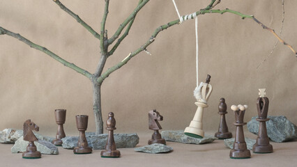 chess piece white king hanging on noose among black chess pieces